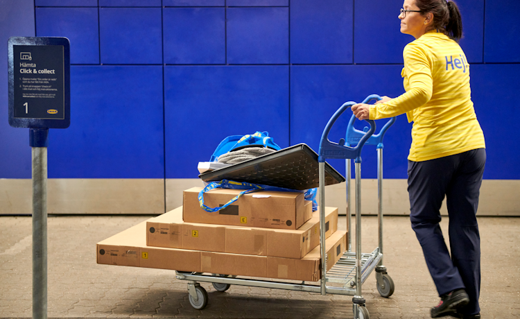 vrouw duwt een karretje met ikea-producten
